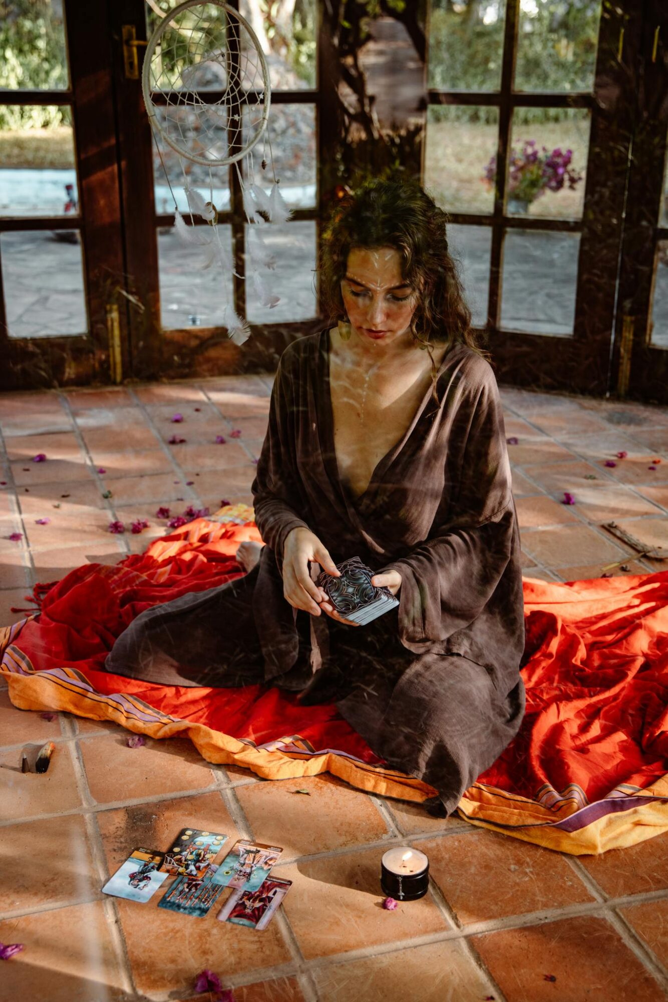 A woman sitting indoors performing a tarot card reading with dreamy ambiance.